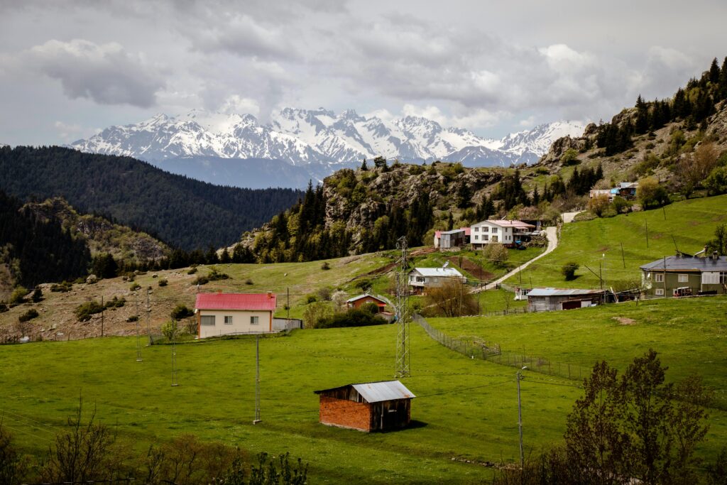 Picturesque mountain village landscape in Artvin, Türkiye with snow-capped peaks and lush greenery.